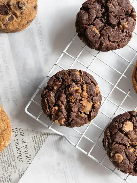 tres galletas de doble chocolate encima de una rejilla blanca