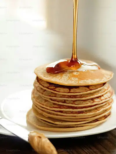 plato blanco con once tortitas apiladas con un chorro de sirope
