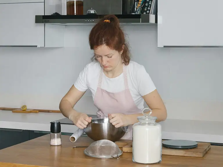 una mujer envolviendo un cuenco con papel film en una cocina
