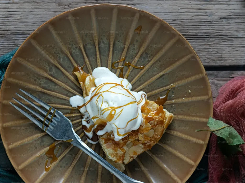 tarta de manzana con almendras y helado de nata en un plato color tierra